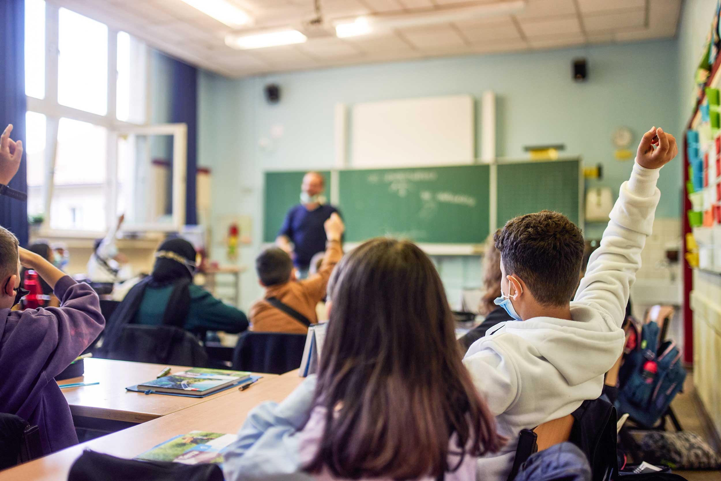 Schulkinder zeigen im Unterricht auf